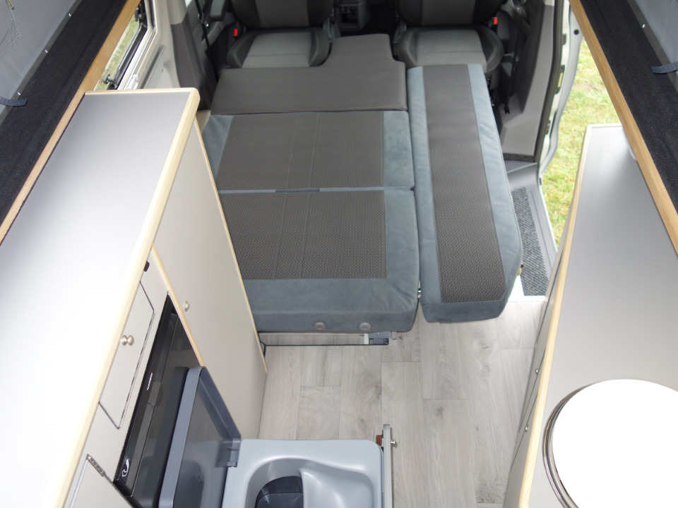Innenansicht des Campmobils Richtung Front mit aufgebauter Liegefläche