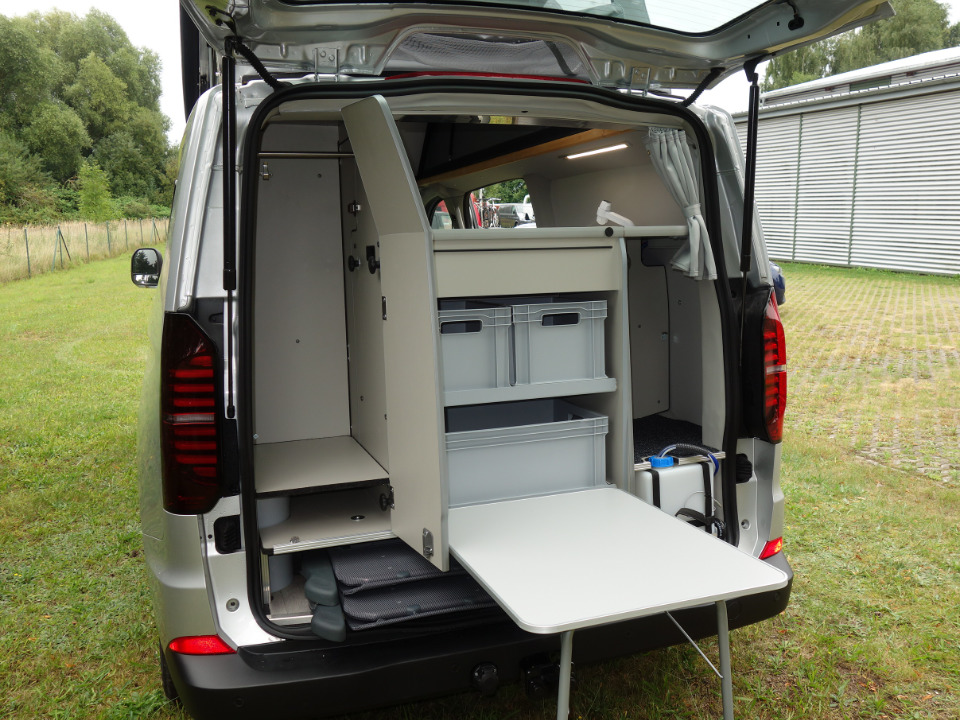 Blick auf die Heckküche des Campmobils mit ausgeklapptem Hecktisch